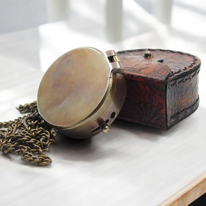 Brass pocket compass placed inside engraved leather case.
