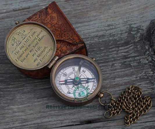 Open brass compass inside premium leather case showing jeweled needle