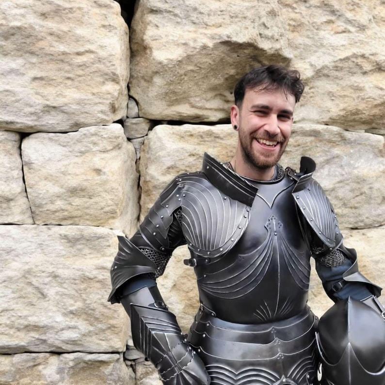 Detailed image showing the sculpted chest plate and ribbed pauldrons of the 15th century gothic knight armor with intricate black finish.