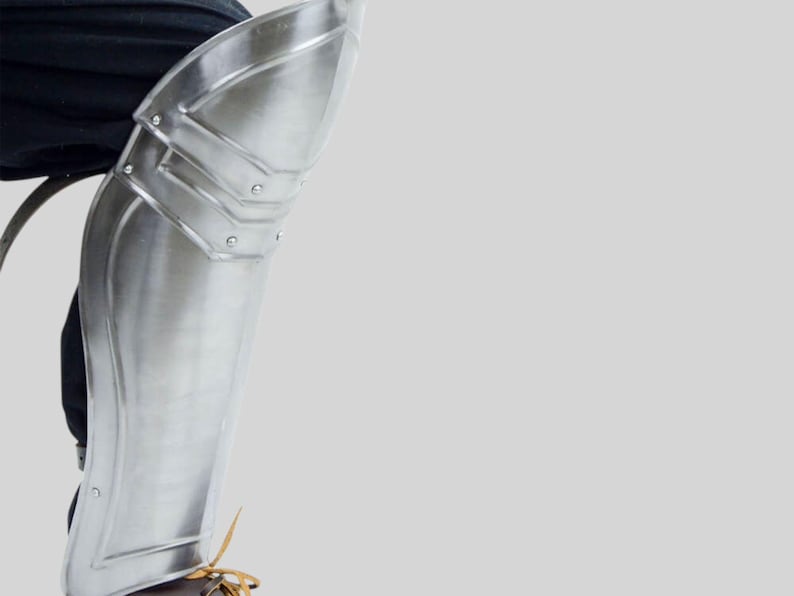 Side profile of knight armor leg greaves with leather straps for historical costume