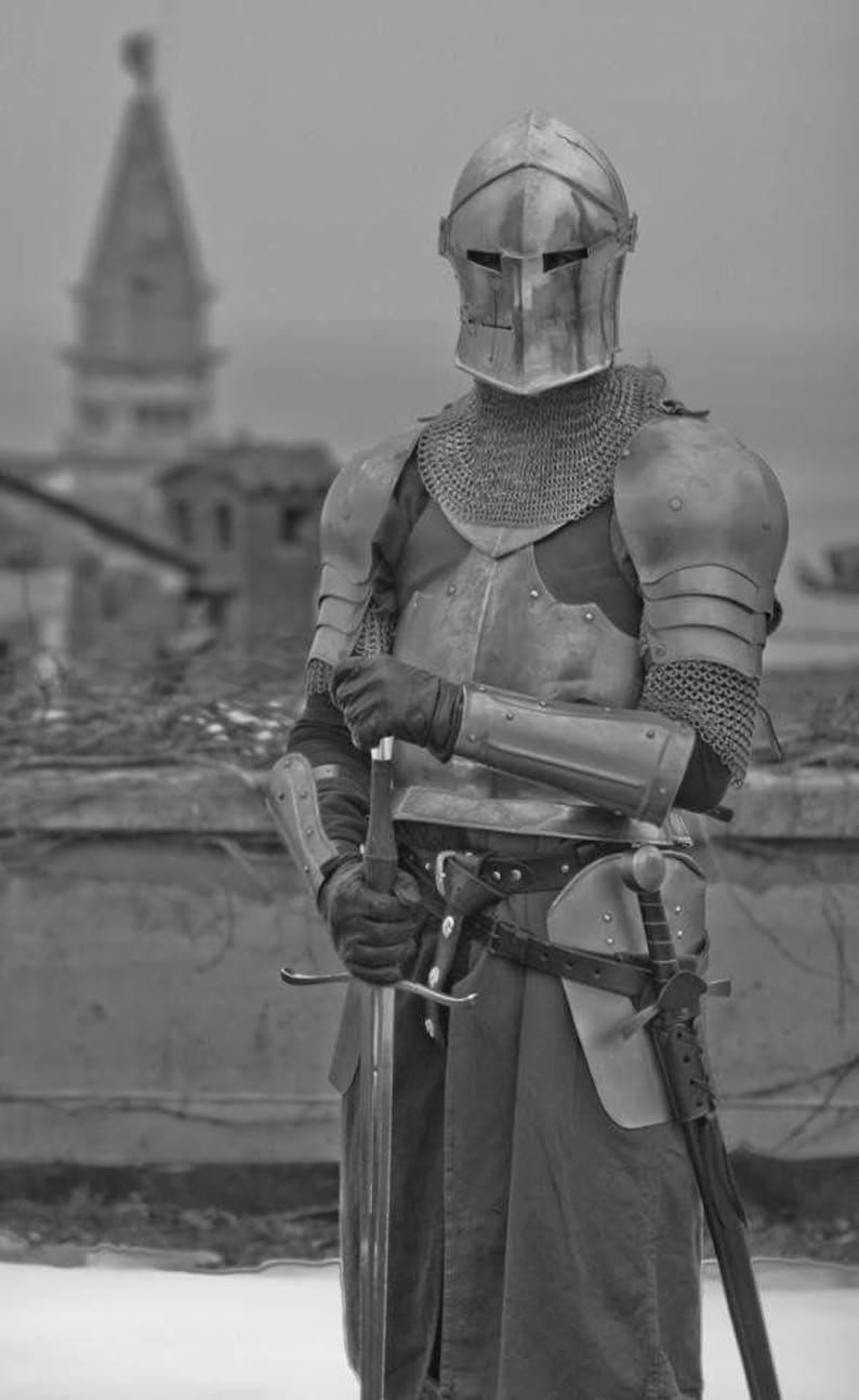 Close-up of enclosed Barbuta helmet with narrow visor slit for medieval knight protection.
