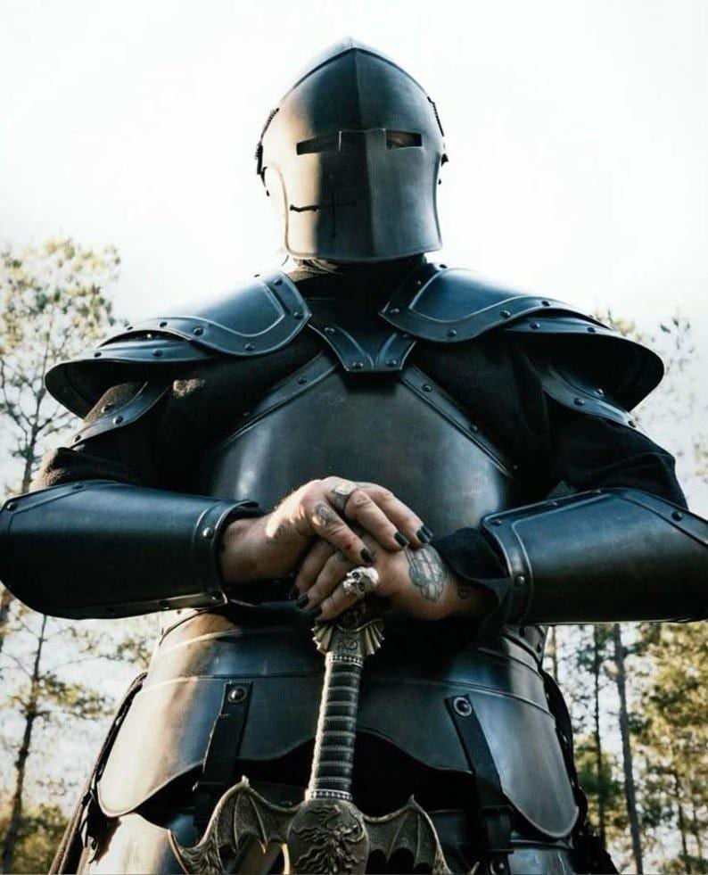 Close-up of black Barbuta-style medieval helmet with visor slit for visibility and protection.