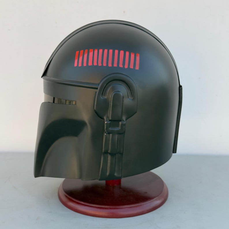 Black and red Mandalorian helmet displayed as sci-fi costume armor for collectors and fans.