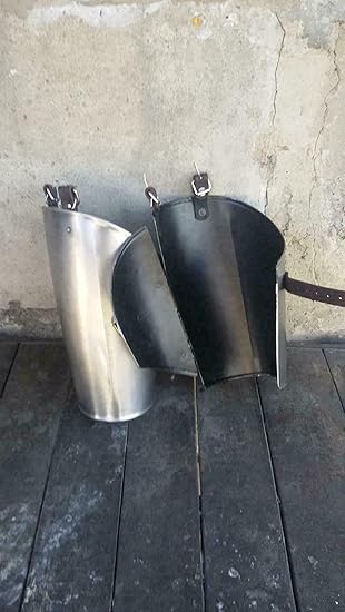 Two metal cowbells on a wooden surface with a concrete wall background.