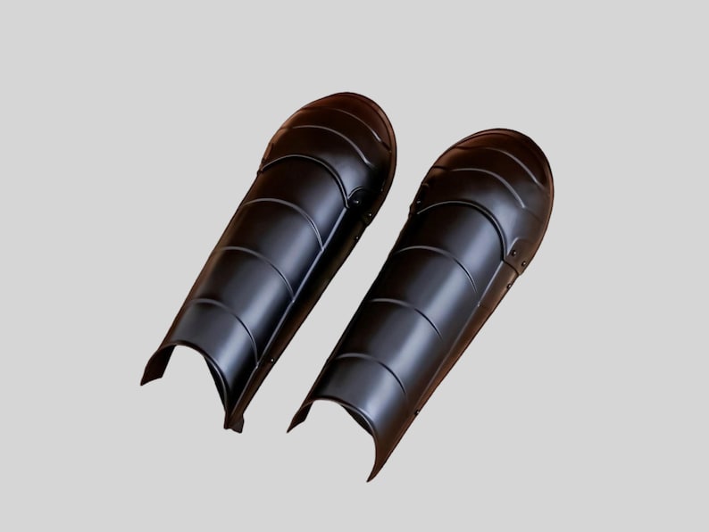 Blackened steel leg greaves with adjustable leather straps for reenactment armor costume