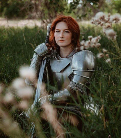Back view highlighting the steel chainmail and full leg armor including greaves, worn as part of a full-body female knight costume.

