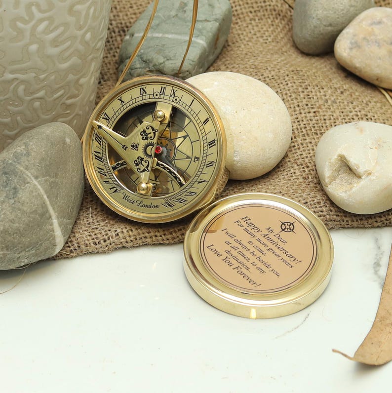 Close-up of engraved message under the sundial lid of a romantic travel compass gift.